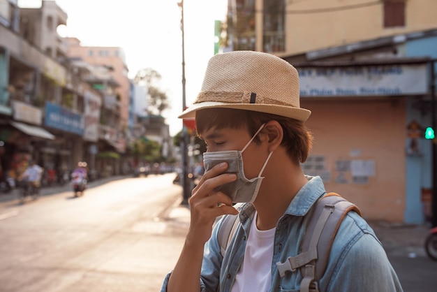 Toeristische man met masker die een kopje koffie drinkt terwijl hij op straatreisconcept loopt in het nieuwe normaal