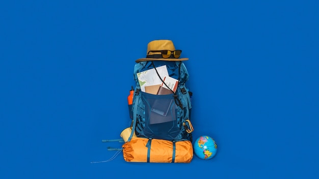 Toeristische planning vakantie met behulp van wereldkaart met andere reisaccessoires in de buurt. concept Bagage met accessoire voor reizigers Vakantie op blauwe kleur achtergrond. Reis rugzak