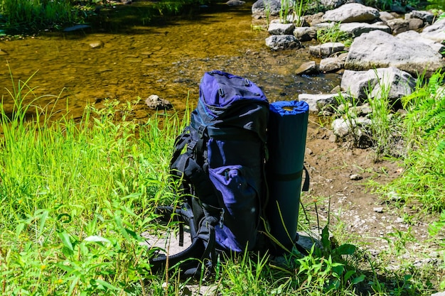 Toeristische rugzak aan een oever van de rivier in het bos