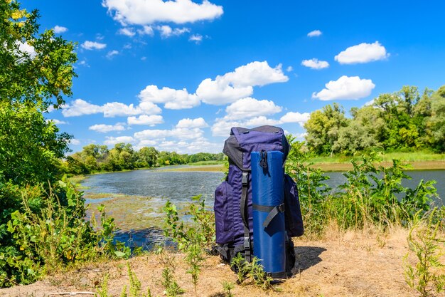 Toeristische rugzak aan een oever van de rivier