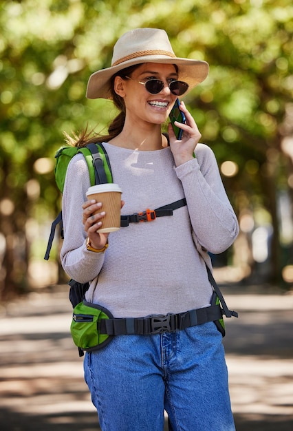 Toeristische rugzak en telefoontje in reizen, bezienswaardigheden en avontuur in de natuur bossen bos en bomen park met koffie Gelukkige glimlach backpacken en pratende vrouw op mobiele communicatietechnologie