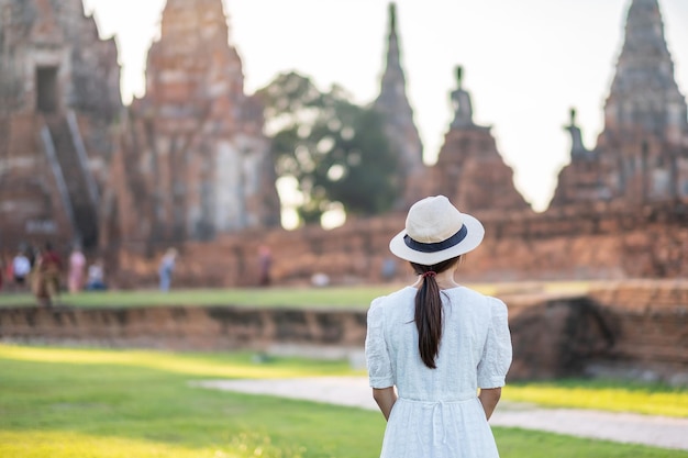 Toeristische vrouw in witte jurk een bezoek aan oude stoepa in Wat Chaiwatthanaram tempel in Ayutthaya Historical Park, zomer, Azië en Thailand reisconcept