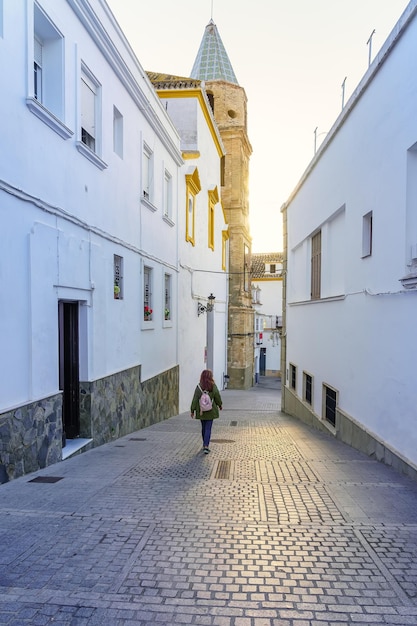 Toeristische vrouw slenteren door de smalle straatjes bij zonsondergang op een zonnige dag Medina Sidonia Cadiz