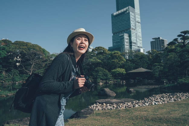 Toeristische vrouw vrolijk lachend reizen foto met camera van de skyline van de stad van osaka met de hoogste wolkenkrabber Abeno tijdens zomervakantie reizen in osaka japan. gelukkig meisje dat onder de blauwe hemel staat