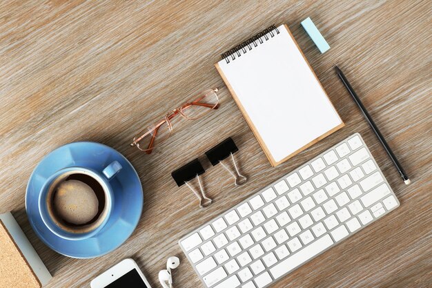 Toetsenbord notitieboekje en kopje koffie op een houten bureau achtergrond bovenaanzicht