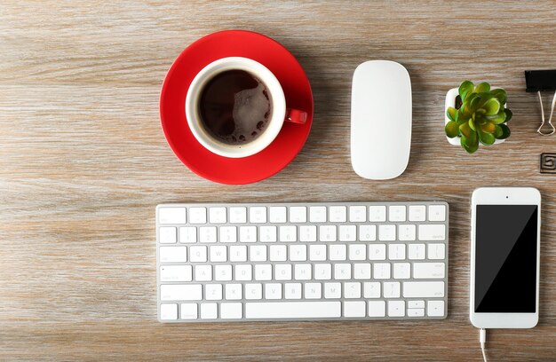 Toetsenbordtelefoon en kopje koffie op een houten bureau achtergrond bovenaanzicht