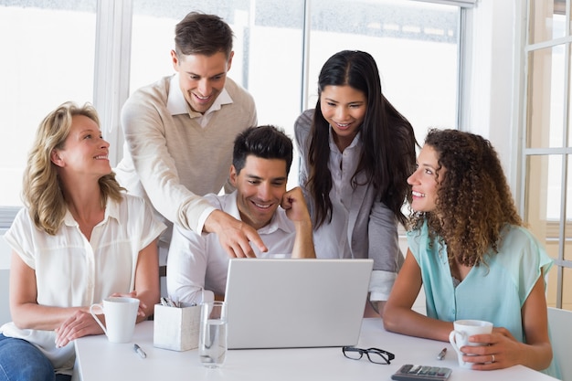 Toevallig glimlachend commercieel team die een vergadering hebben die laptop met behulp van