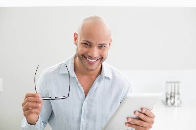 Toevallige glimlachende mens die digitale tablet thuis gebruiken