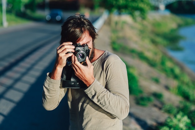 Toevallige hipstermens die foto maken die retro camera in openlucht in het park met behulp van