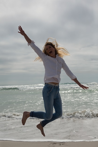 Toevallige jonge vrouw die bij strand springt