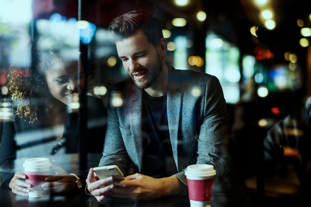 Toevallige mens die mobiele telefoon in de koffie met behulp van