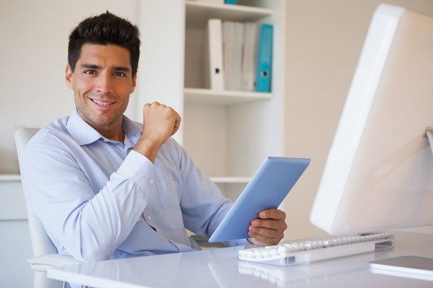 Toevallige zakenman die zijn tablet houdt bij zijn bureau