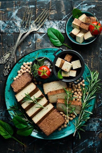 Сыр тофу Органический соевый сыр тофу с розмарином, разрезанным на кусочки на тарелке на каменном фоне