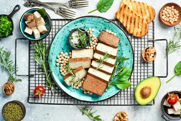 Formaggio tofu formaggio di soia tofu biologico con rosmarino tagliato a pezzi su un piatto su uno sfondo di pietra