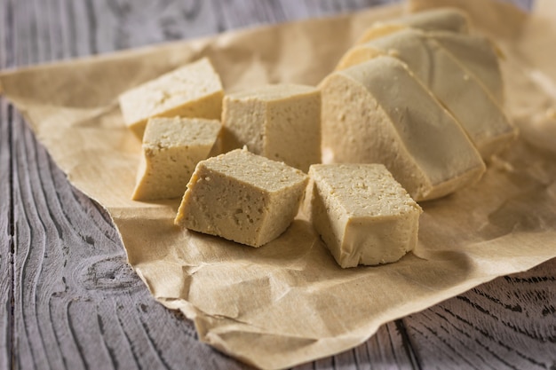 Formaggio di tofu su un pezzo di carta su un tavolo di legno. formaggio di soia. prodotto vegetariano.