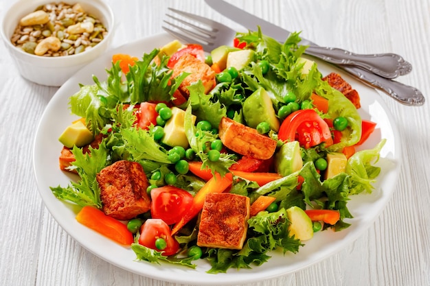 Tofu salad with greens and vegetables on plate