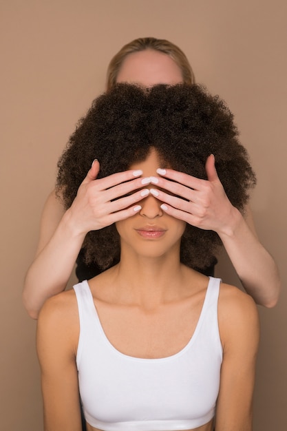 Togerherness. A dark-haired woman and a blonde woman standing back to back