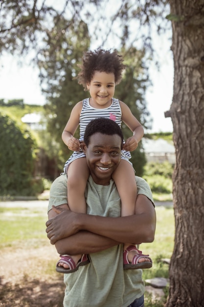 Together.  man spending time in the park with his daughter and looking cheerful