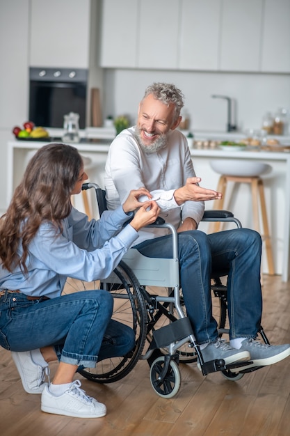 Together. Pretty woman taking care about her handicapped husband and smiling nicely