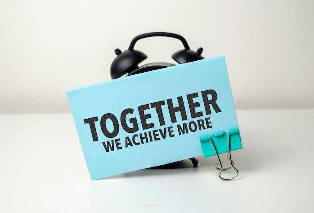 Together we achieve more is written in a blue sticker near a black alarm clock