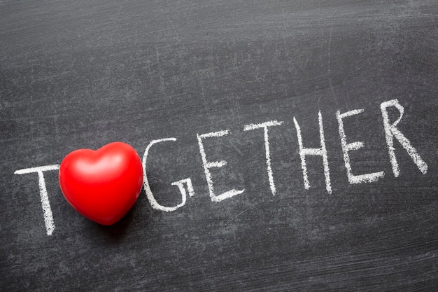 Together word handwritten on blackboard with heart symbol