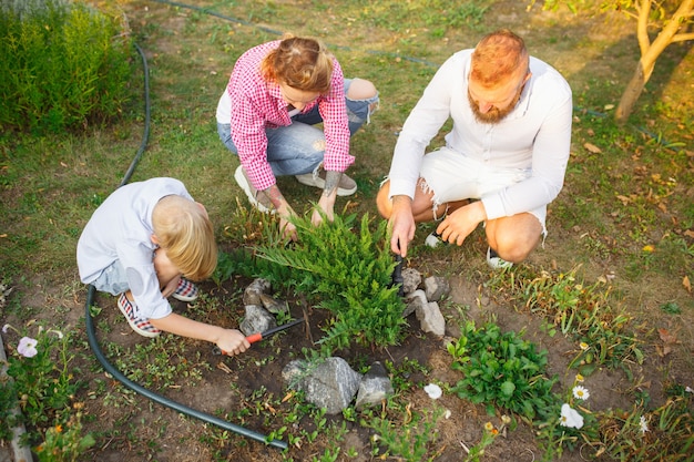 Togetherness and happiness. Happy family during plant care in a garden outdoors. Love, family, lifestyle, harvest, autumn concept. Cheerful, healthy and lovely. Organic food, agriculture, gardening.