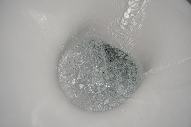 Toilet bowl flush. Water splash. Water flushes down toilet bowl. Water close-up.