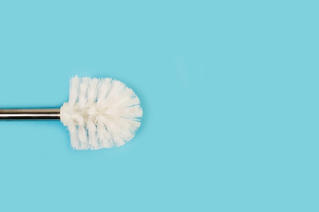 A toilet brush on a light blue background with copy space
