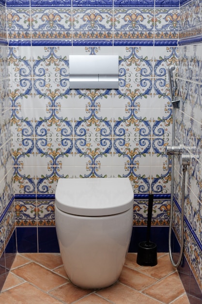 Toilet in home. Flash button on wall tiled with pattern ceramic