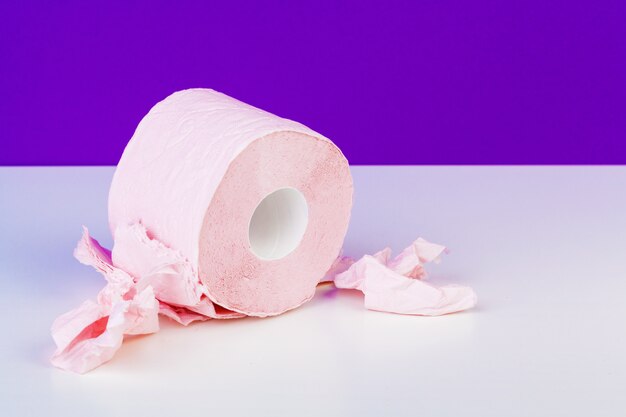 Toilet paper rolls isolated on white table with purple 