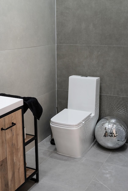 Toilette e piccolo lavabo in un bagno semplice con pavimenti e rivestimenti grigi