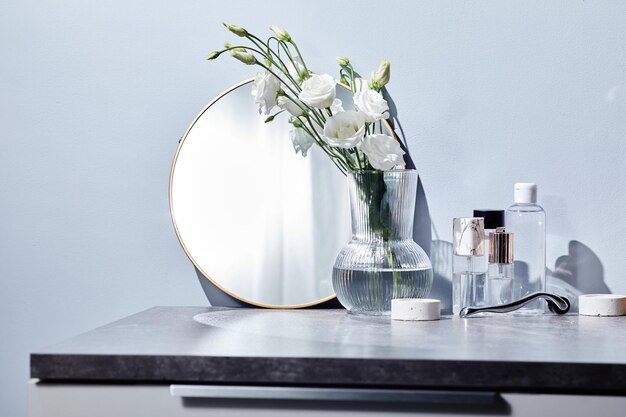 Toilet table for woman with mirror cosmetics and flowers in vase in bathroom