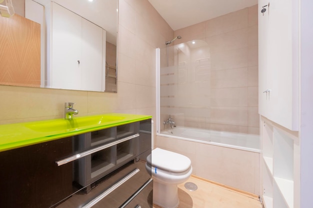 Toilet with black cabinet and green glass sink in a vacation rental apartment