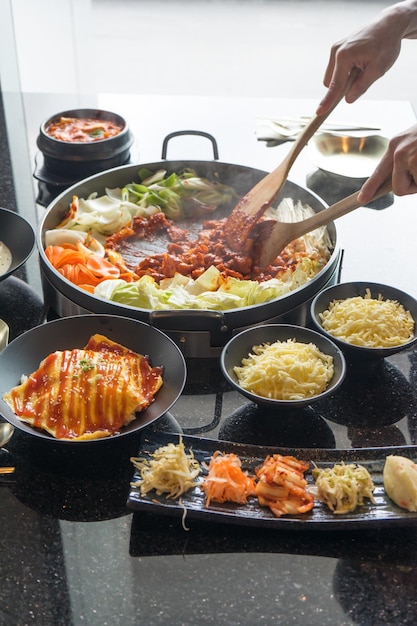 Tokboki Koreaans traditioneel eten, hete en pittige rijstwafelcombinatie en breng bladerdeeg met kaas en groente aan op de zwarte tafel