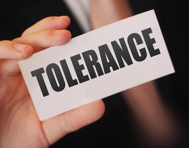 Слова толерантности на карточке в руке бизнесмена Социальная концепция против дискриминации на рабочем месте