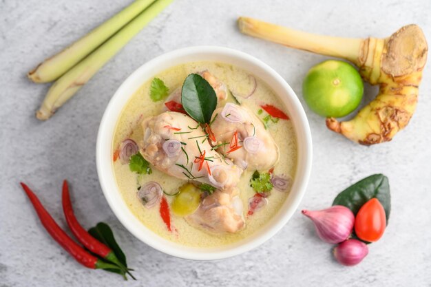 Photo tom kha kai in a bowl with kaffir lime leaves lemongrass red onion galangal and chilli