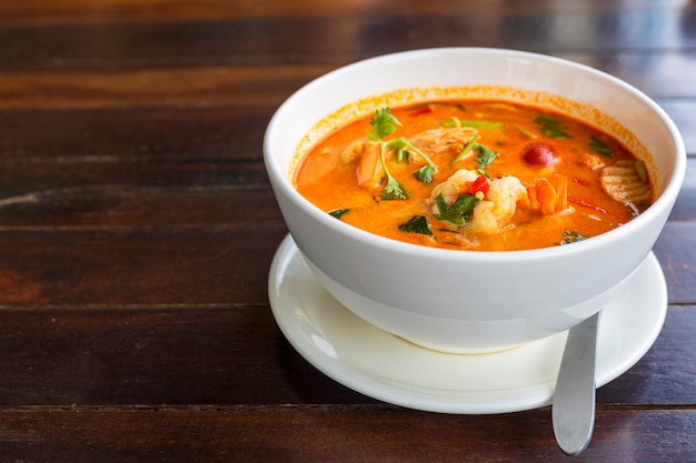 Tom Yam kung Pittige Thaise soep met garnalen in witte kom op houten tafel.