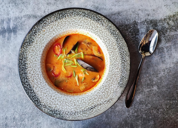 Tom Yam Kung soup (Thai cuisine) on gray stone restaurant table top view