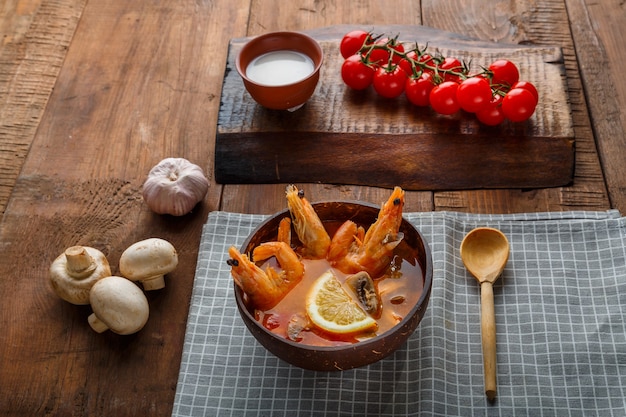 Tom yam soep met garnalen en kokosmelk op tafel op een servet naast melk en een houten lepel. Horizontale foto