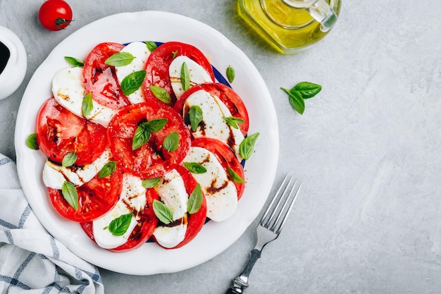 Tomaat basilicum mozzarella Caprese salade met balsamico azijn en olijfolie Bovenaanzicht grijze stenen achtergrond