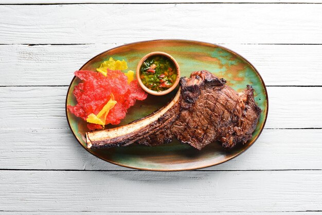 Tomahawk steak medium rare to rare on a plate On a white wooden background Top view Free copy space