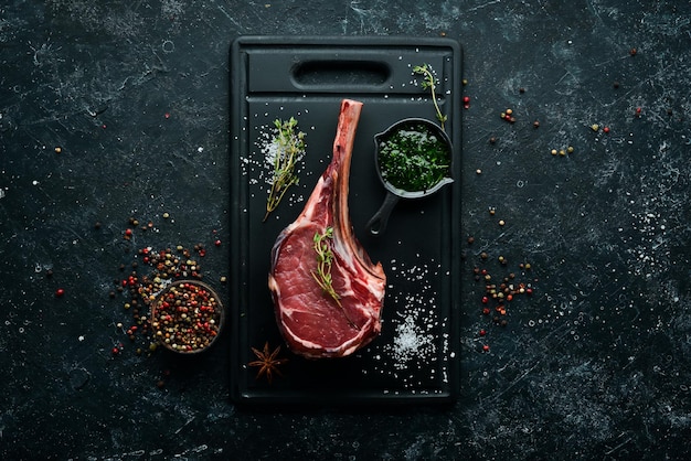 Tomahawk steak Raw steak on a black background Top view Free copy space