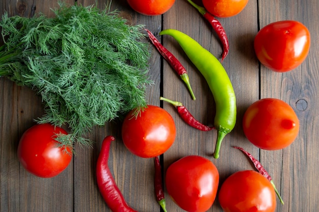 Tomaten, hete pepers en dille op een houten tafel