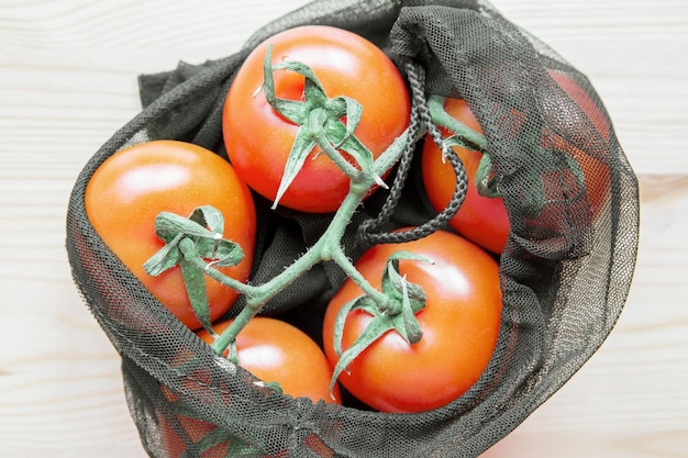 Tomaten in herbruikbare boodschappentas op een houten tafel Het concept van nul afval en milieuvriendelijke levensstijl Geen plastic bovenaanzicht