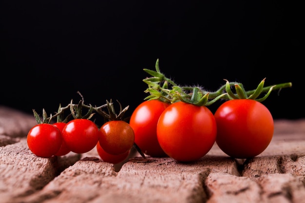 Tomaten in houten plaat op zwarte achtergrond