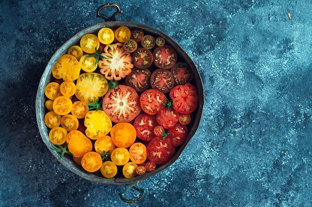 Tomaten in plakjes van verschillende kleuren worden weergegeven als een verloop op een donkere achtergrond.