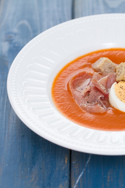 Tomaten koude soep met ei en jamon op witte schotel