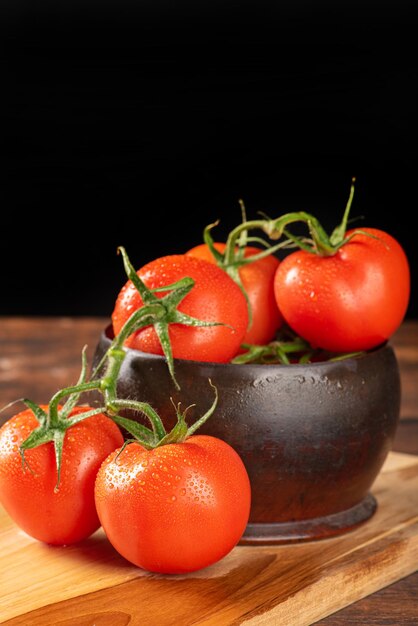 Tomaten mooie tomaten geplaatst in een houten pot op een rustieke tafel zwarte achtergrond selectieve focus