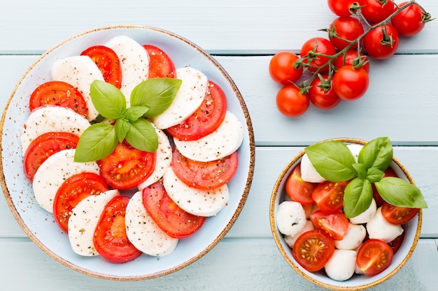 Tomaten, mozzarellakaas, basilicum en kruiden op grijs leisteen bord. Italiaanse traditionele caprese salade ingrediënten. Mediterraans eten.