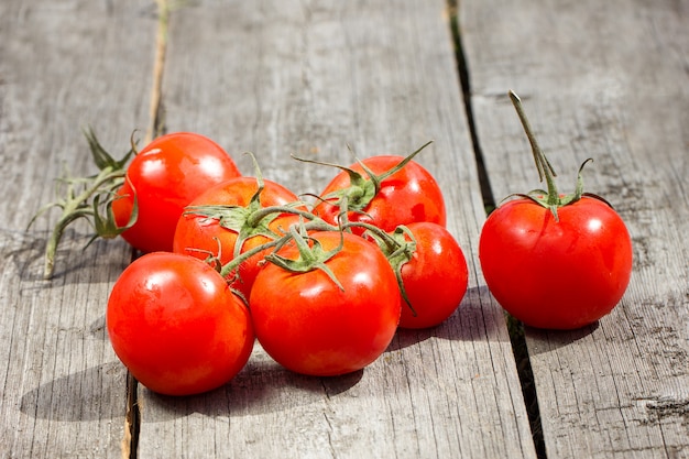 Tomaten op een houten lijst Tomaten met kruiden voor het behoud op de oude houten lijst worden gekookt die. Biologisch voedsel. Hard licht